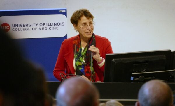 Dr. Constance Cepko holds a microphone and smiles